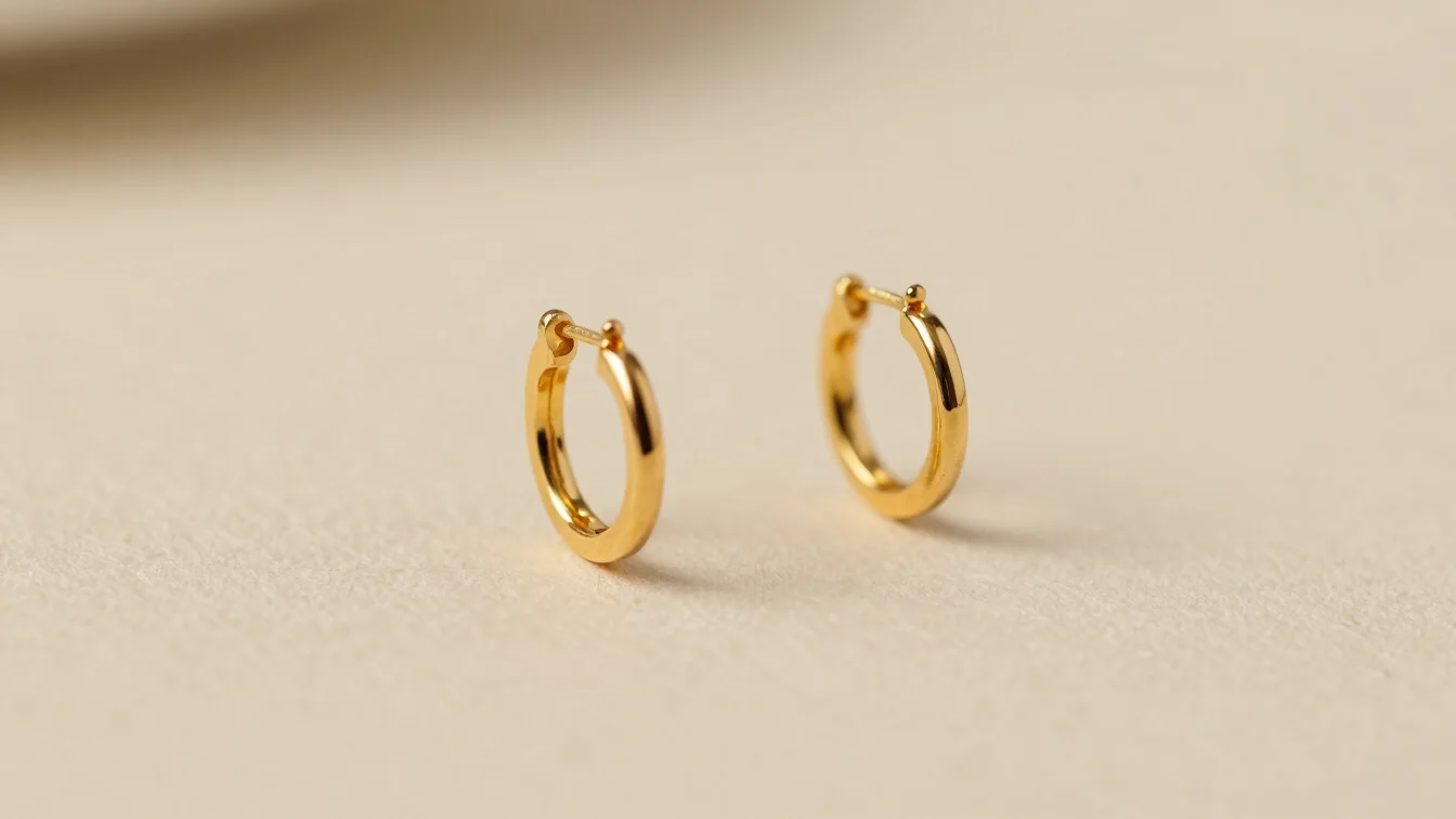 Macro photograph of small gold hoop earrings on neutral background, warm ambient light