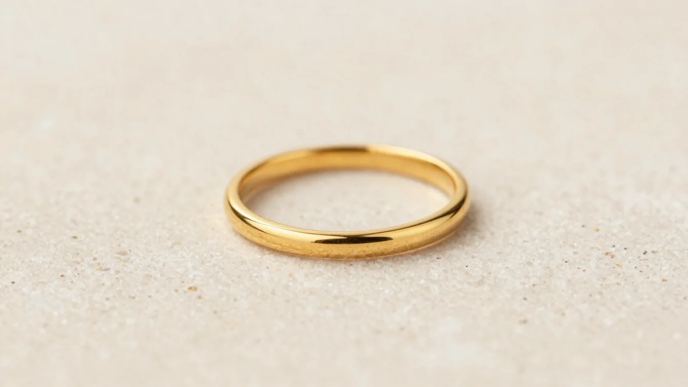 Macro photograph of a delicate gold band ring on smooth stone surface, soft warm lighting